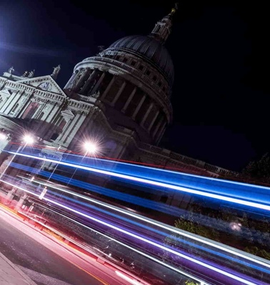 Night view of St. Paul's Cathedral in London with light trails from passing vehicles.