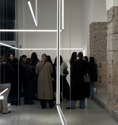 A group of people congregated in a modern art gallery with geometric lighting.