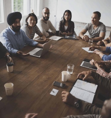 A group of diverse business professionals engaged in a meeting around a conference table.