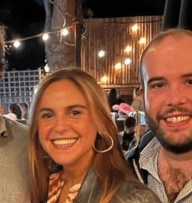 Three friends smiling at an outdoor event during nighttime.