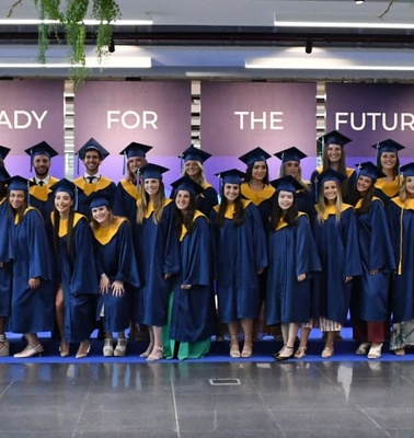 A group of graduates wearing caps and gowns standing in a line during a graduation ceremony.