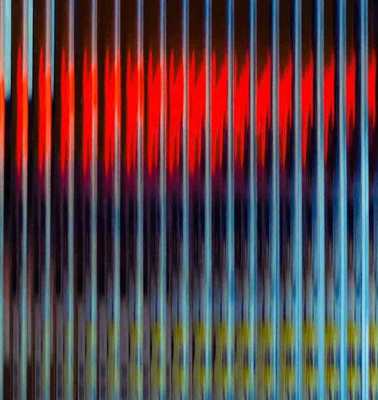 Abstract image featuring vertical blurred lines in various shades of red, blue, and yellow.