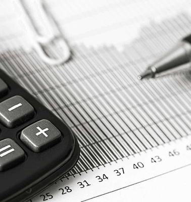 A calculator, pen, and financial documents on a desk indicating financial planning or accounting.