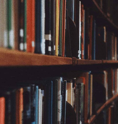 A close-up view of books arranged in a library shelf with a focus on their spines, displaying a variety of colors and textures.