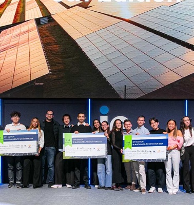 A group of people stands on a stage holding large checks with a backdrop of solar panels.