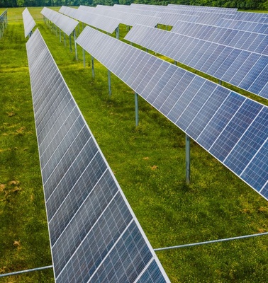 Aerial view of solar panels arranged in rows on green grass.