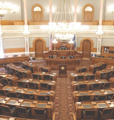 A spacious legislative chamber with rows of wooden desks and ornate decor.
