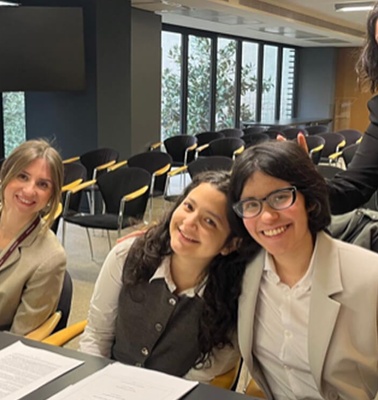 A group of four young women smiling and posing together at a table during an event.