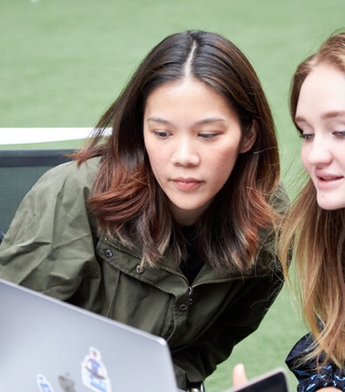 Two IE students looking to a laptop