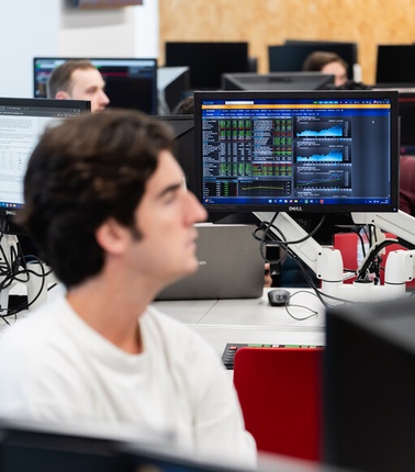 A student is focused on a computer screen displaying data analysis in a classroom setting.