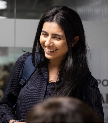 A woman smiles broadly in a business environment.