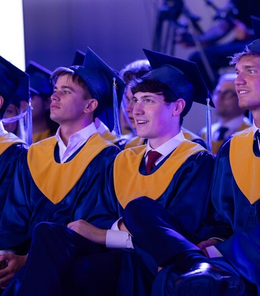A group of graduates wearing caps and gowns during a ceremony.