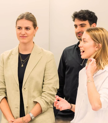 A group of young professionals engaged in conversation in a modern office setting.