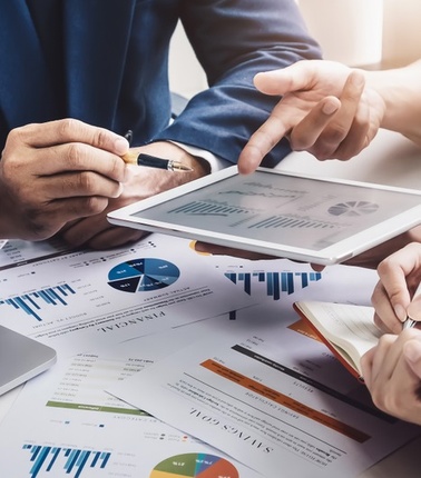 A business meeting focusing on data analysis with charts and graphs displayed on documents.