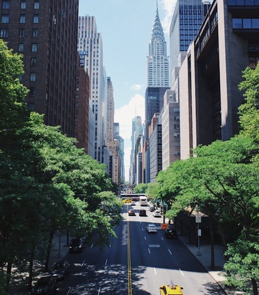 A bustling city street with tall buildings and a yellow taxi.