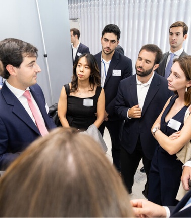 A group of professional people in business attire, engaged in a serious discussion at an event.