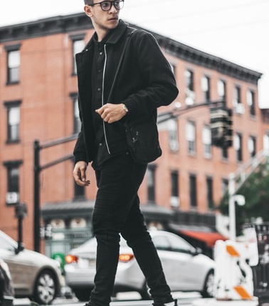 A young man in stylish casual attire walking confidently on an urban street.