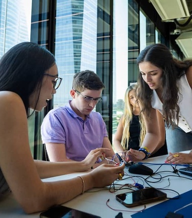 A group of young people collaborating on a project with technology in a modern office environment.