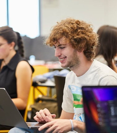 A group of students working on laptops in a collaborative study environment.