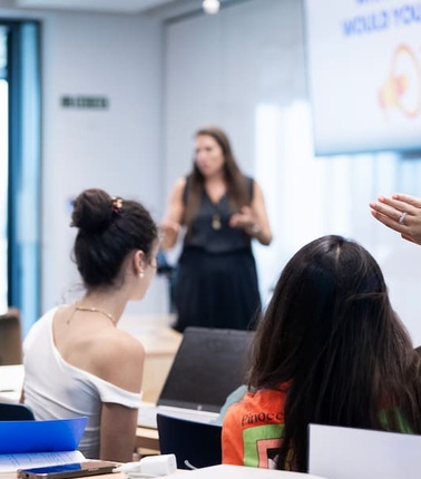 A group of students in a classroom actively engaging with a speaker.