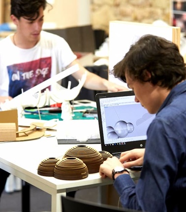 Two students working on architectural models in a studio.