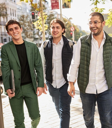 A group of four young adults walking together on a sunny day.