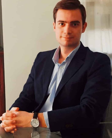 A young man in business attire sitting at a table.