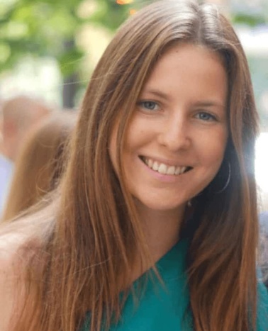 A smiling woman with long brown hair wearing a green top.