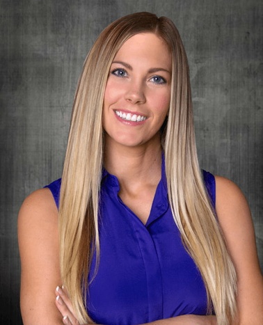 A professional portrait of a smiling woman with long blonde hair wearing a blue blouse.