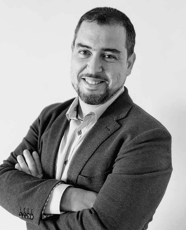 Black and white photo of a smiling man in a suit with crossed arms