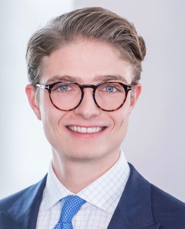 Portrait of a smiling young man in business attire with glasses.