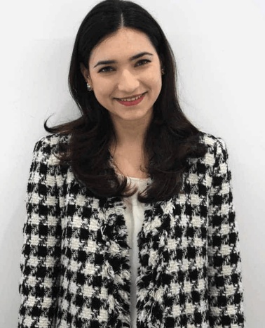 A woman in a black and white checkered jacket smiling at the camera against a plain white background.