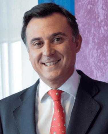 A professional portrait of a smiling man wearing a suit and red tie.