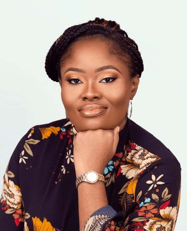 Portrait of a confident woman in a floral top, resting her chin on her hand.