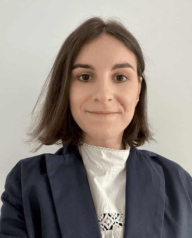 A portrait of a smiling woman wearing a business suit with a decorative white blouse.