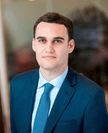 A professional portrait of a man in a blue suit and tie.