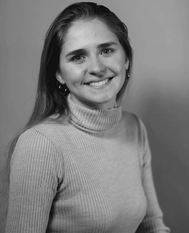 A black and white portrait of a smiling young woman wearing a turtleneck sweater.