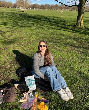 A woman sitting on the grass in a park, enjoying a sunny day.