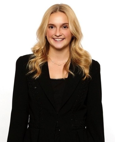 A smiling young woman wearing a black blazer and a necklace, posing for the camera.