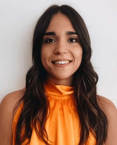 A portrait of a smiling woman with long brown hair, wearing an orange top.