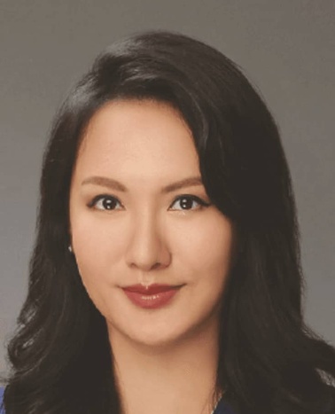 Portrait of a young woman with long dark hair wearing a blue top.