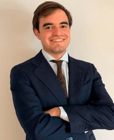 A man in a blue suit with a striped tie smiling at the camera