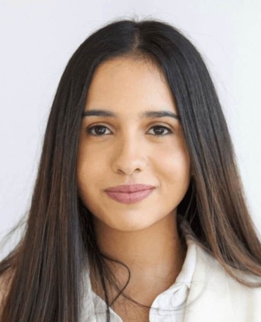 Portrait of a young woman with long dark hair, smiling gently at the camera against a light background.