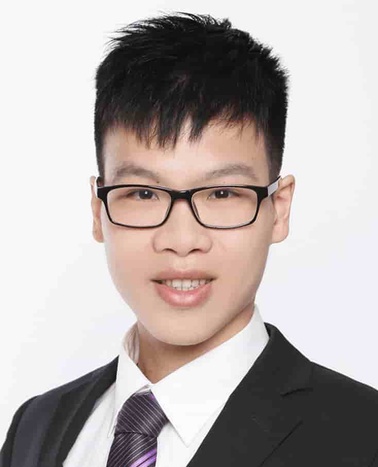 Portrait of a young Asian man wearing glasses, a black suit, and a purple tie on a white background.