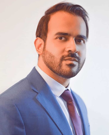 A portrait of a man in a blue suit and red tie, looking at the camera with a serious expression.