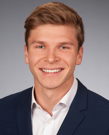 A smiling young man in a formal suit.