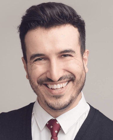 Portrait of a smiling man wearing a suit and a red tie.