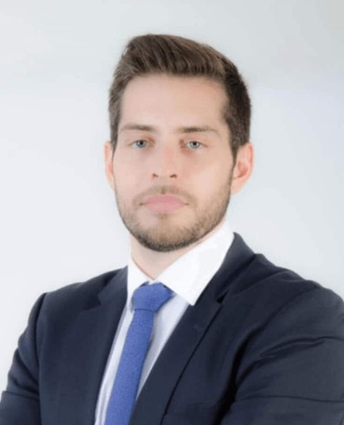 A professional headshot of a young man in a suit and tie.