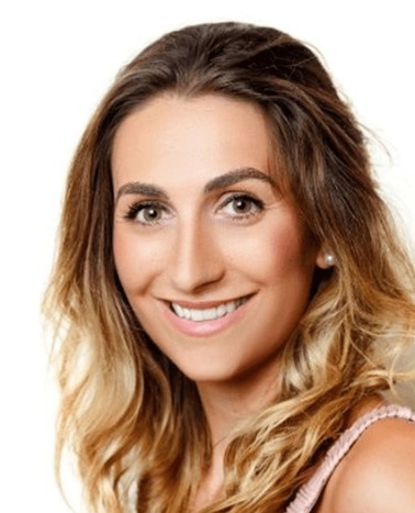 Portrait of a smiling woman with long, wavy blond hair and a pink top against a white background.