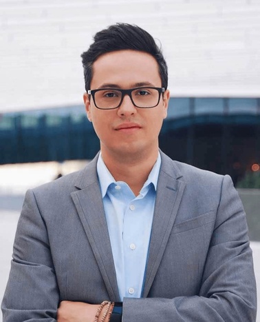 A professional looking young man in a business suit standing in front of a modern building.